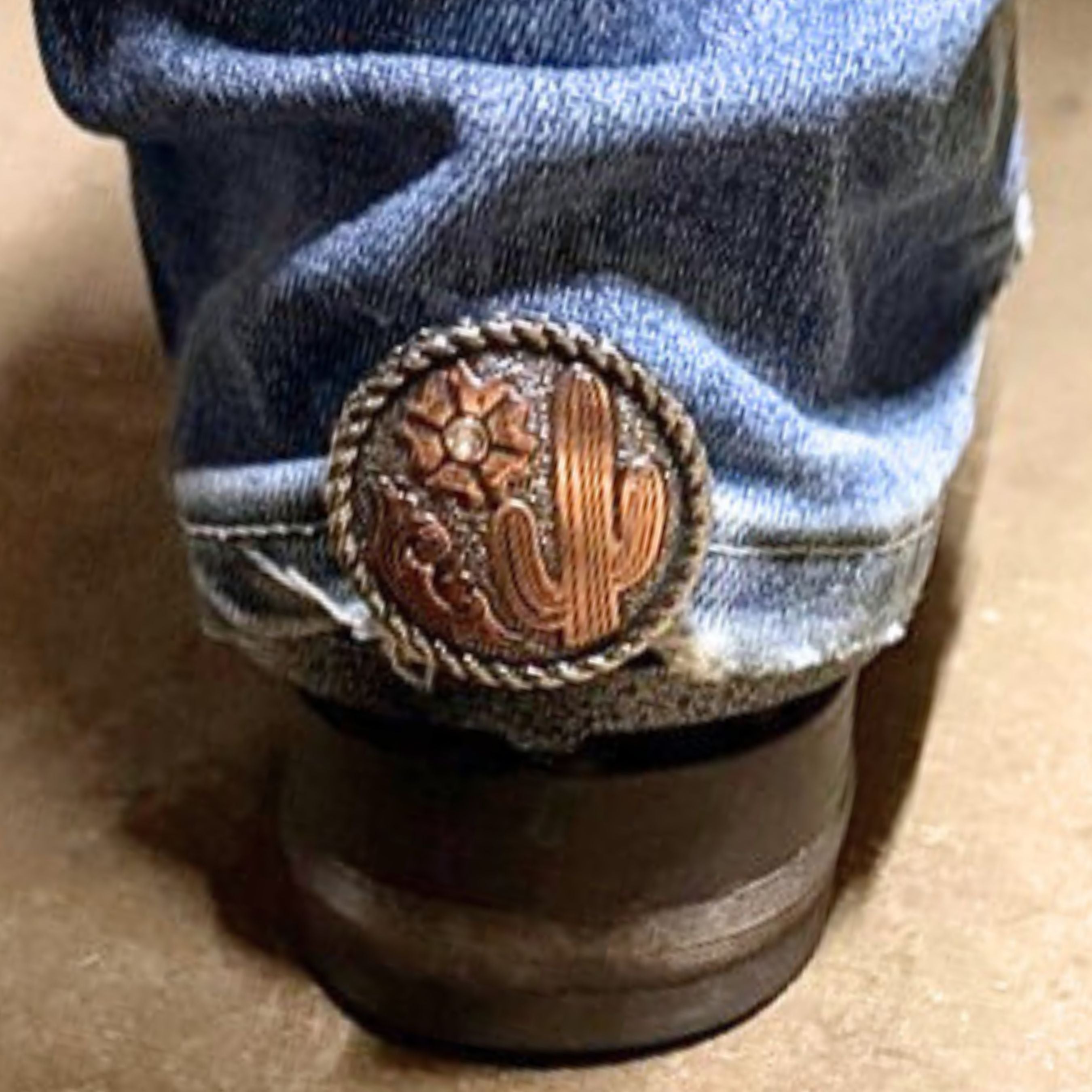 Cactus Flower Clear Stone Cowgirl Cuff attached to the back of a cowboy boot, helping keep jean hems off the ground while adding Southwestern western style.